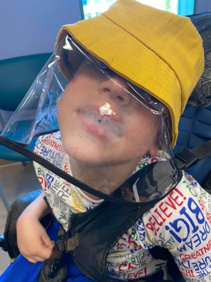 Jacob in a yellow hat with a clear face shield